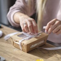 woman packing box with handmade candles. DIY gift concept. young woman entrepreneur earns on her creativity