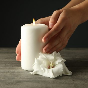Mourning candles in hands, on a dark background.